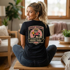 Woman wearing a black t-shirt with a graphic design sitting on a coffee table in a living room.