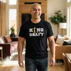 Man wearing a black t-shirt with 'King of the Draft' text in a living room.