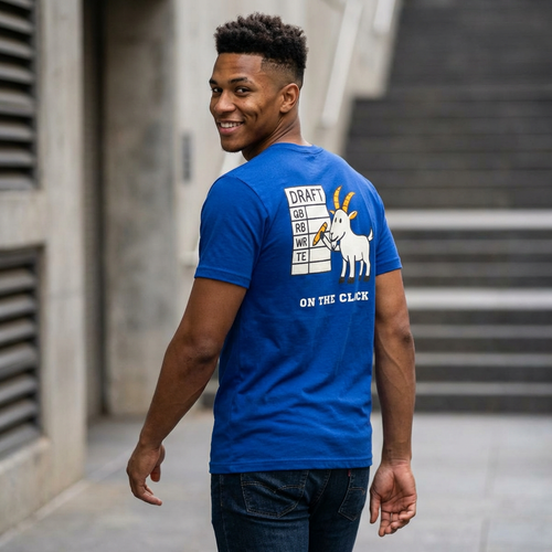 Man wearing a blue t-shirt with a graphic design on the back, standing outdoors.