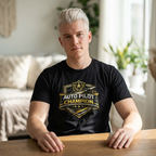 Person wearing a black t-shirt with 'Auto Pilot Champion' design in a room with a couch and plants.