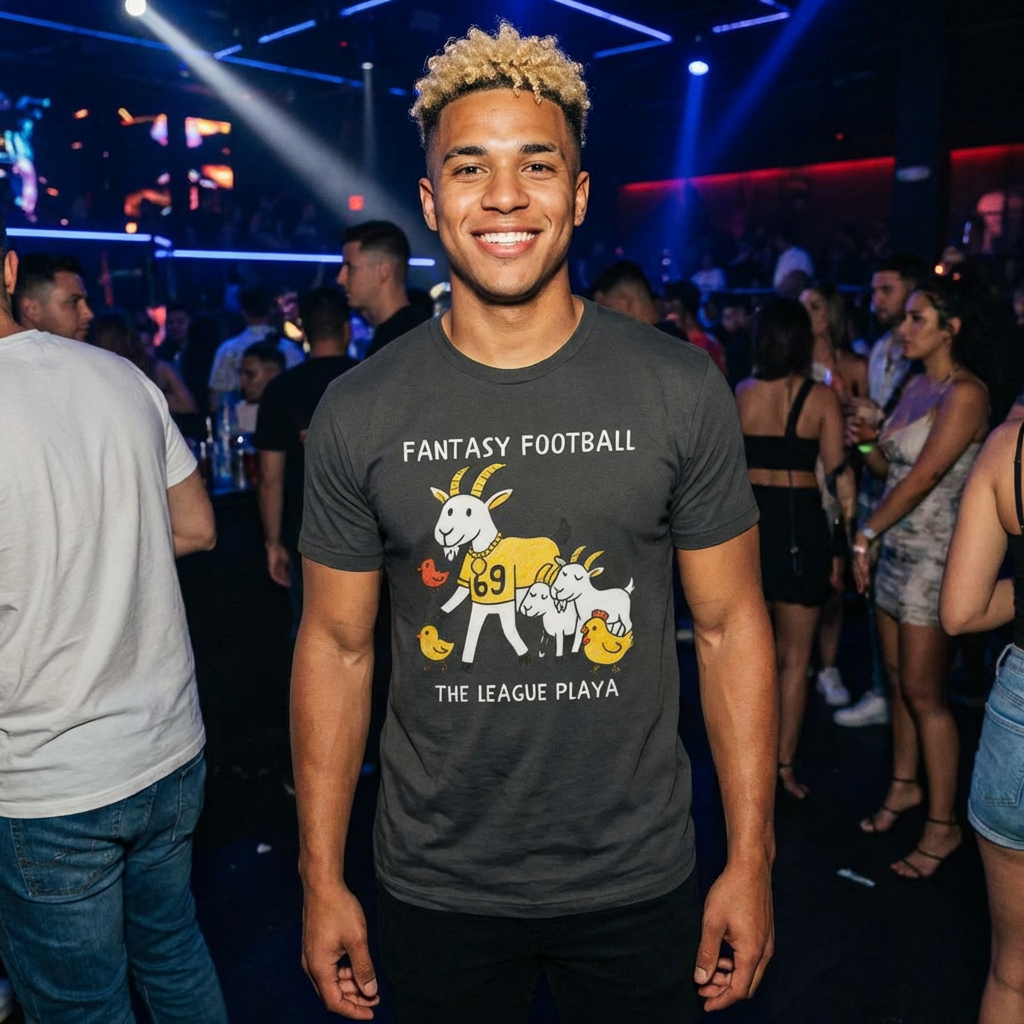 Man wearing a 'Fantasy Football' t-shirt at a lively event with people and lights in the background.