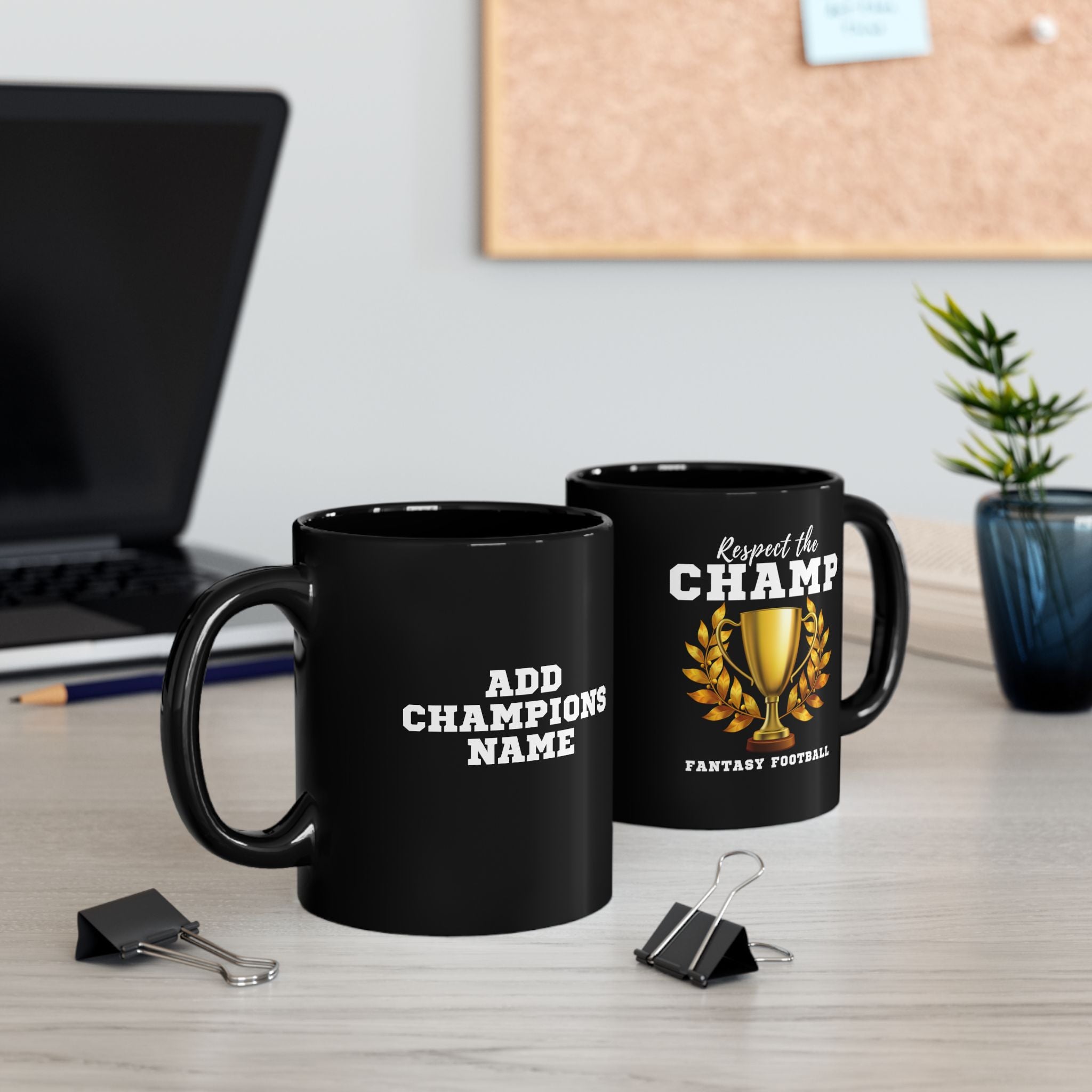 Two black mugs with text on a desk, one with a trophy graphic and the other with text.